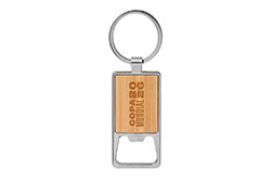 Llavero destapador modelo Kidrink que combina a la perfección funcionalidad y estilo. Presenta una resistente estructura metálica con acabado brillante y un elegante panel frontal de bambú barnizado. Sus medidas exactas son de 6 cm por 3,2 cm por 3,5 cm. Cada unidad se entrega en una ecológica caja de regalo Kraft que incluye una delicada bandeja interior de terciopelo negro. Resulta un accesorio sumamente práctico y sofisticado, ideal para destacar su marca en obsequios empresariales que buscan integrar un toque natural.
