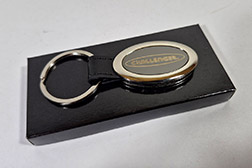 Llavero oval premium de metal y símil cuero. Este excelente llavero importado combina un marco plateado de brilloso con un núcleo central de metal negro. Una correa de símil cuero negro une el cuerpo ovalado de forma segura a un robusta argolla chata. Diseñado específicamente para personalización mediante grabado láser de alta precisión, que revela el metal base para un logotipo nítido y duradero. Se entrega en una elegante caja de presentación individual de cartón negro mate con inserto aterciopelado, perfecto para regalos corporativos de alta gama. Medidas generales de 6cm x 2.5cm, cuerpo oval de 4.5cm x 2.5cm, materiales metal y símil cuero.